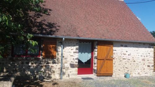 a brick house with a red door and a window at La Closerie de la Trottinière in Moncor