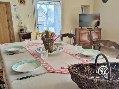 a dining room table with plates and a basket on it at La Closerie de la Trottinière in Moncor