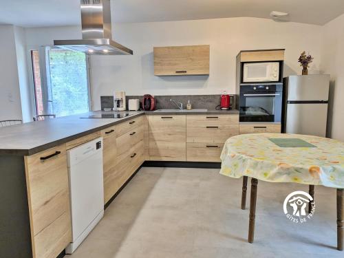 a kitchen with wooden cabinets and a table in it at Gîte du Hérisson, 6 personnes 