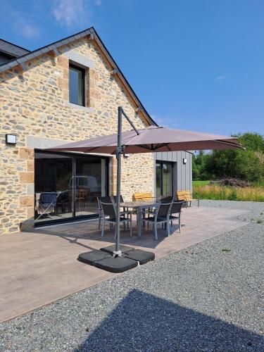 a patio with a table and an umbrella at Un air de campagne in Saint-Pierre-la-Cour