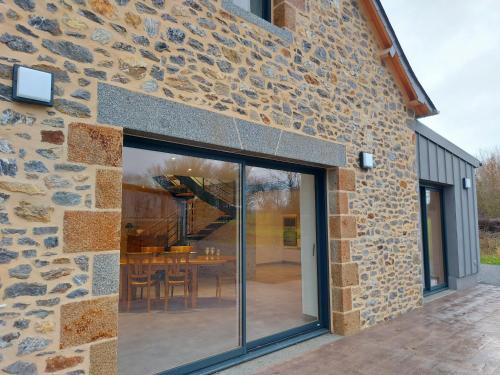 a stone house with glass doors and a patio at Un air de campagne in Saint-Pierre-la-Cour