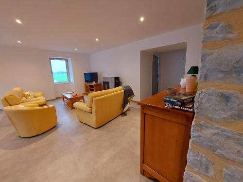 a living room with yellow chairs and a stone wall at Un air de campagne in Saint-Pierre-la-Cour
