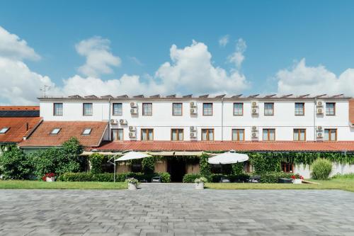 a large white building with umbrellas in a courtyard at Hotel Maroli Mikulov in Mikulov
