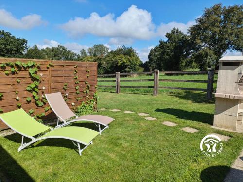 two chairs sitting in a yard next to a fence at Les gallinettes in Neuilly-le-Vendin