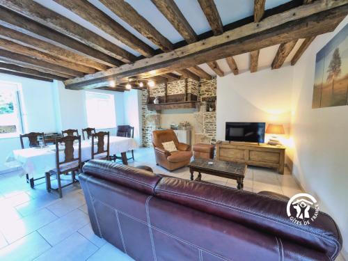 a living room with a leather couch and a table at Les gallinettes in Neuilly-le-Vendin