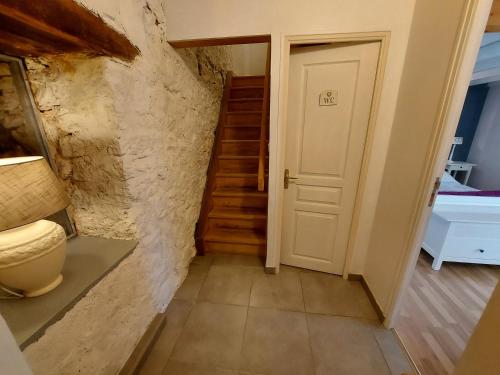 a hallway with stairs and a white door at Le Moulin de Gratte Sac in Voutré