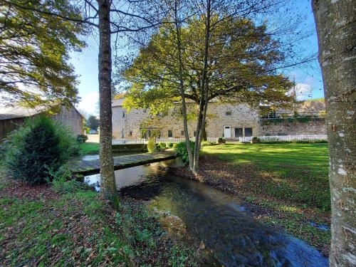 a park with a wooden bench next to a creek at Le Moulin de Gratte Sac in Voutré