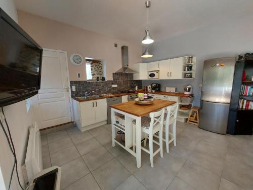 a kitchen with white cabinets and a table in it at Le Moulin de Gratte Sac in Voutré
