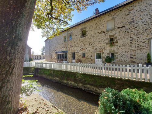a building with a white fence next to a river at Le Moulin de Gratte Sac in Voutré