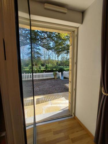 a sliding glass door with a view of a yard at Le Moulin de Gratte Sac in Voutré