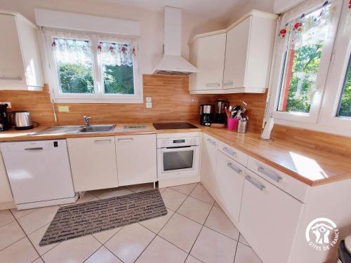 a white kitchen with white cabinets and windows at La Semondière in Saint-Thomas-de-Courceriers