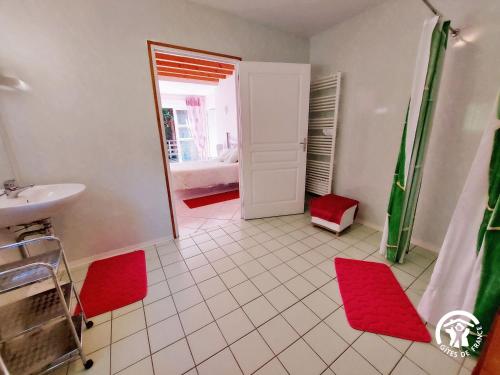 a bathroom with a sink and red rugs at La Semondière in Saint-Thomas-de-Courceriers