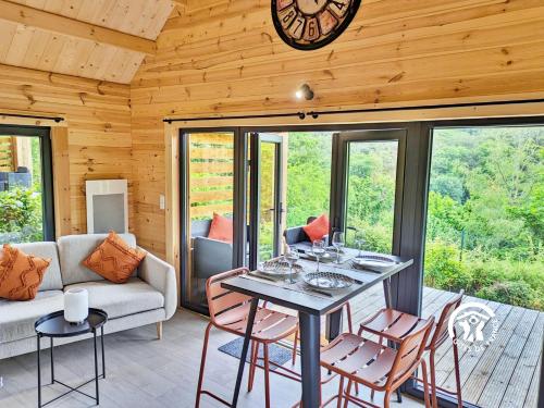 a living room with a table and chairs and a clock at Chalet 25 Le Vicoin, Camping de Coupeau, 4 personnes in Saint-Berthevin