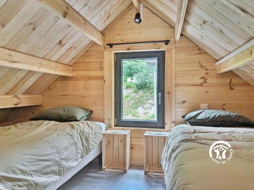 two beds in a log cabin with a window at Chalet 25 Le Vicoin, Camping de Coupeau, 4 personnes in Saint-Berthevin