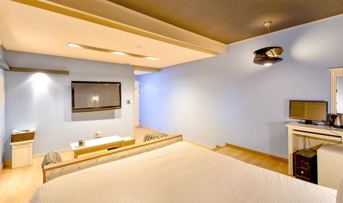 a large room with a bed and a tv on a wall at Airtel in Busan