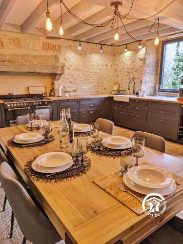 a kitchen with a wooden table with plates and glasses at Gîte Les Haies de Tresmes, jusqu'à 6 personnes in Gesvres