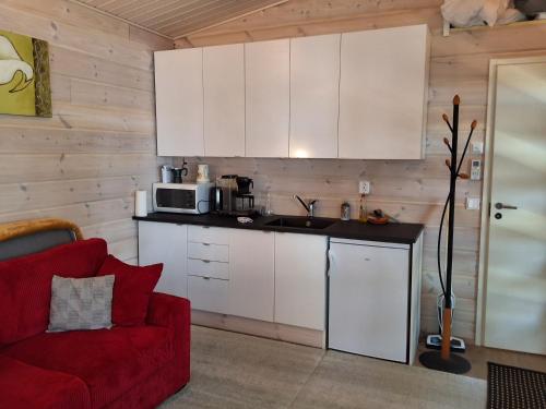 a kitchen with white cabinets and a red couch at Modern holiday cabin in Saimaa in Enonkoski