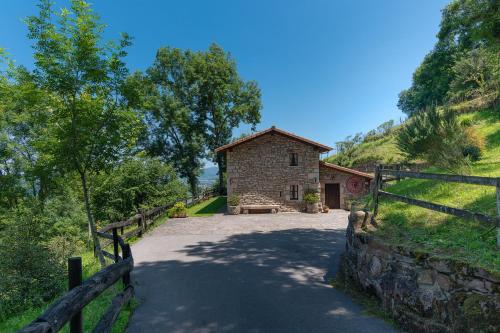 a stone house with a fence next to a road at El currillo preciosa casa rural al lado cabarceno in Argomilla