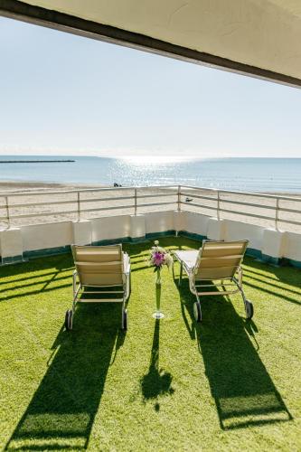two chairs sitting on the grass next to the beach at Hotel Polamar in Santa Pola