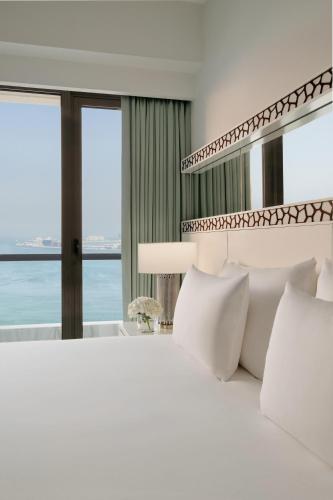a bedroom with a white bed with a view of the ocean at JA Ocean View Hotel, Jumeirah Beach Dubai in Dubai