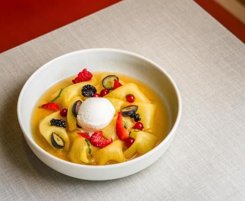 a bowl of soup with fruit and ice cream in it at Falkensteiner Residences Jesolo in Lido di Jesolo