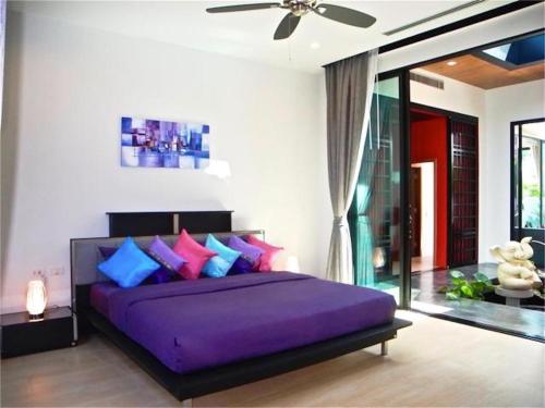 a bedroom with a purple bed with colorful pillows at Baan Bua Nai Harn 3 bedrooms Villa in Nai Harn Beach