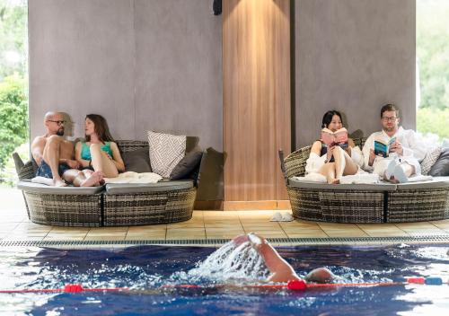 a group of people sitting around a swimming pool at Vale Resort in Hensol