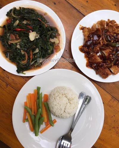 three plates of food with rice and vegetables on a table at Syamsi Village in Bira