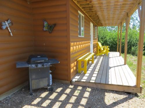 a porch of a cabin with a grill and a smoker at Orchard View Bed and Breakfast in Moose Jaw