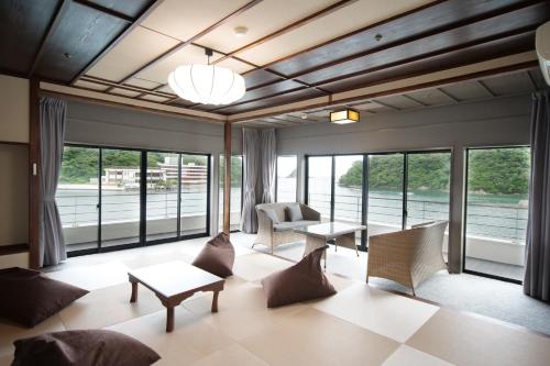 a living room with chairs and tables and windows at TAOYA Nachikatsuura in Nachikatsuura