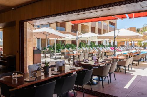 a restaurant with tables and chairs and umbrellas at Oakridge Hotel & Spa in Kfardebian