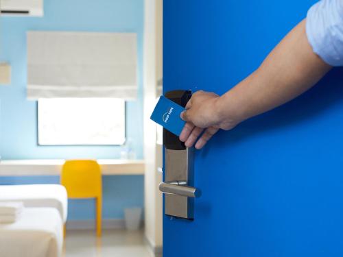 a person holding a blue door with their hand at HOP INN Phrae in Phrae
