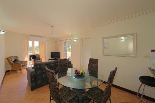 a dining room with a glass table and chairs at Bargara Shoreline Apartments in Bargara