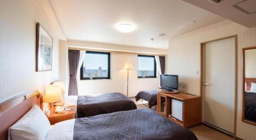 a hotel room with two beds and a television at Albert Hotel in Akita