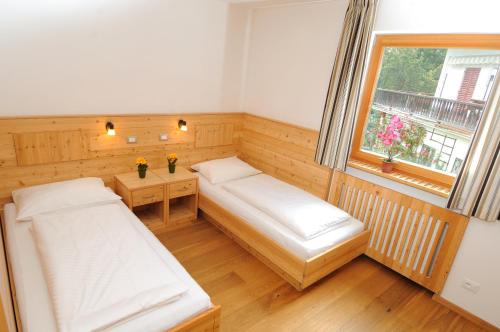 a small room with two beds and a window at Residence Nussbaumer in Siusi