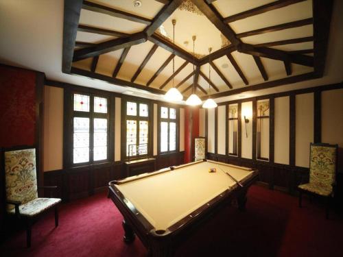 a room with a pool table and two chairs at Unzen Kanko Hotel in Unzen