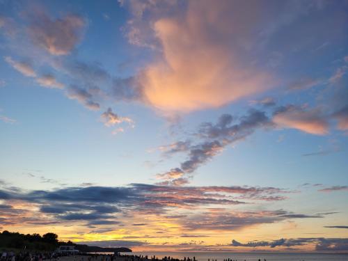un gruppo di persone in piedi sulla spiaggia al tramonto di Willa Nad Morzem a Władysławowo
