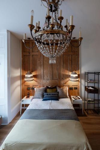 a bedroom with a large bed with a chandelier at Green Maison Westfield in London