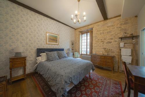 a bedroom with a bed and a table and a chandelier at Les Petits Cousins Du Québec - Chambres D’hôtes à Domme in Domme