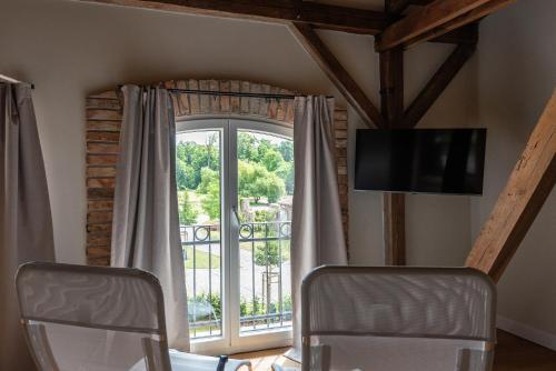 a room with a window with two chairs and a tv at Storchenhof Blumenow in Blumenow
