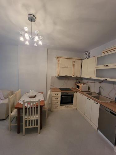 a kitchen with a table and a small kitchen with white cabinets at Henri's Apartments Vlore in Vlorë