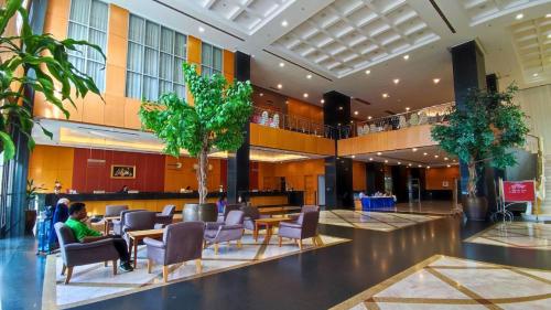 Eine Hotellobby mit Stühlen, Tischen und Bäumen in der Unterkunft Diamond Plaza Hotel in Surat Thani
