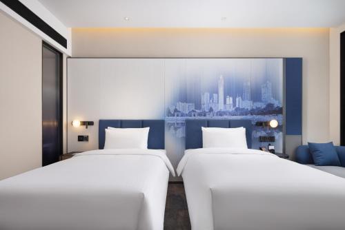 two beds in a room with a view of a city at Hampton By Hilton Dongguan Nancheng Xiping in Baima