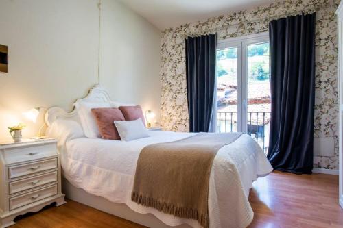 a bedroom with a white bed and a window at La Casa de Ethel en norte de España VV-2427-AS in Cangas de Onís
