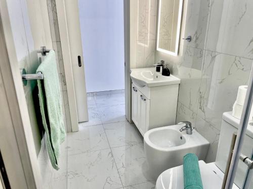 a white bathroom with a sink and a toilet at GuestHost - Penthouse with Jacuzzi in Gozo Island! in Marsalforn