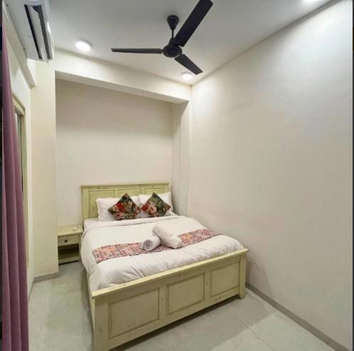 a bedroom with a bed with a ceiling fan at Nirvana City of Music Khopoli in Pali