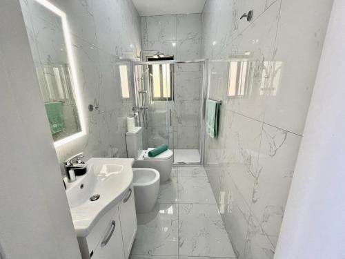 a white bathroom with a toilet and a sink at GuestHost - Penthouse with Jacuzzi in Gozo Island! in Marsalforn