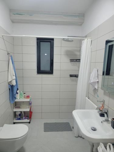 a white bathroom with a toilet and a sink at Henri's Apartments Vlore in Vlorë