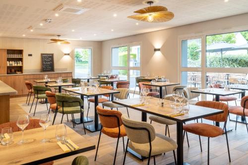 a restaurant with tables and chairs and windows at Sure Hotel by Best Western Tours Sud in Chambray-lès-Tours