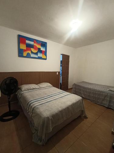 ein Schlafzimmer mit zwei Betten und einem Gemälde an der Wand in der Unterkunft Kitnet Mobiliada Espaço inteiro in Porto Seguro